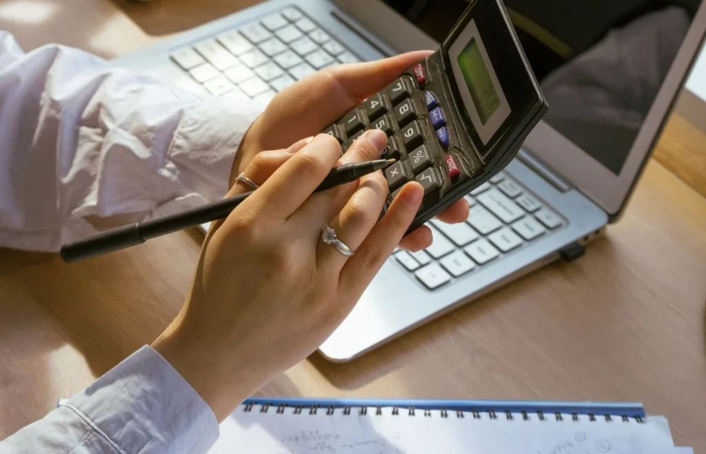 Mãos usando uma calculadora e um computador durante organização financeira.
